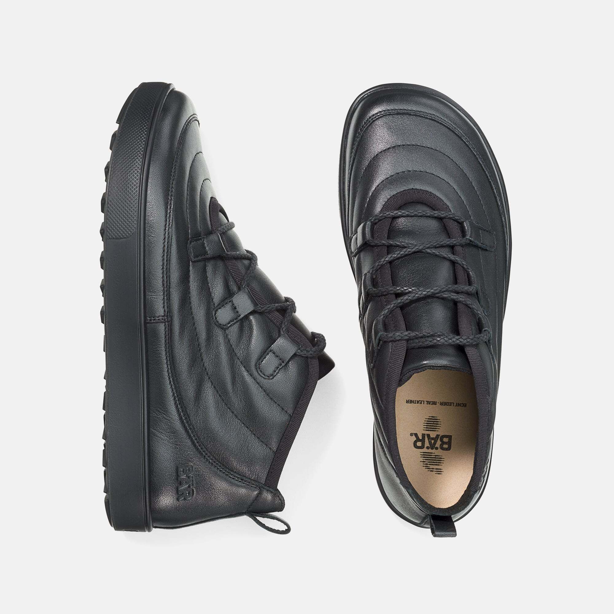 Schwarze BÄR Stiefeletten. Leder, Schnürung, breite Sohle. Draufsicht auf zwei Schuhe, Sohle mit Logo.