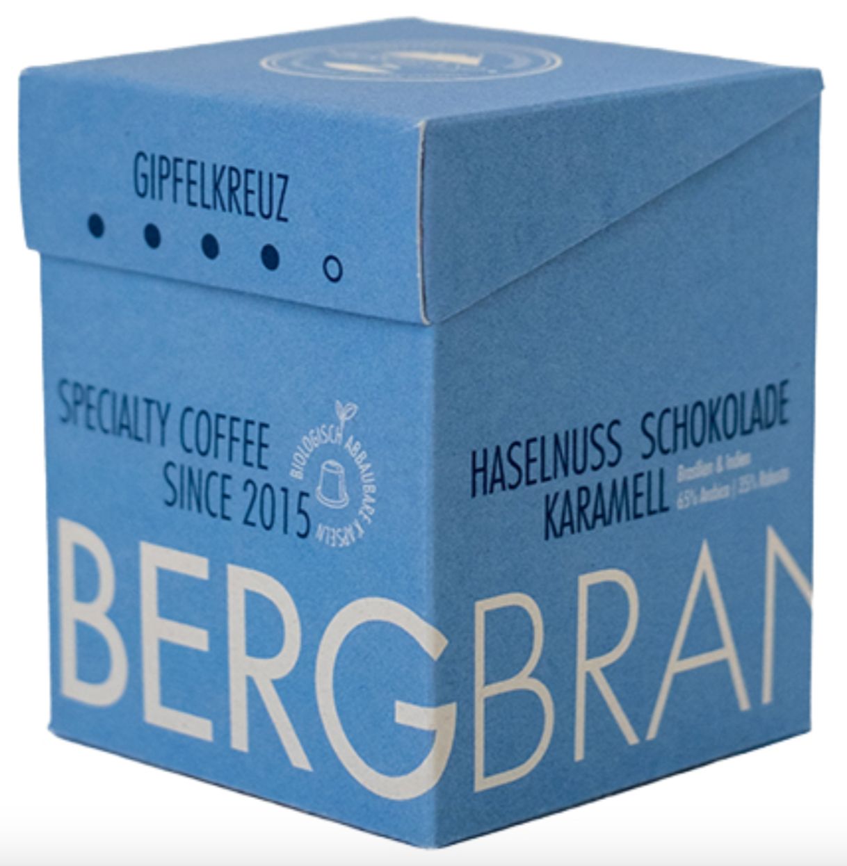 Blaue Schachtel mit BERGBRAND-Logo, Gipfelkreuz, Specialty Coffee. Text: Haselnuss Schokolade, Karamell.