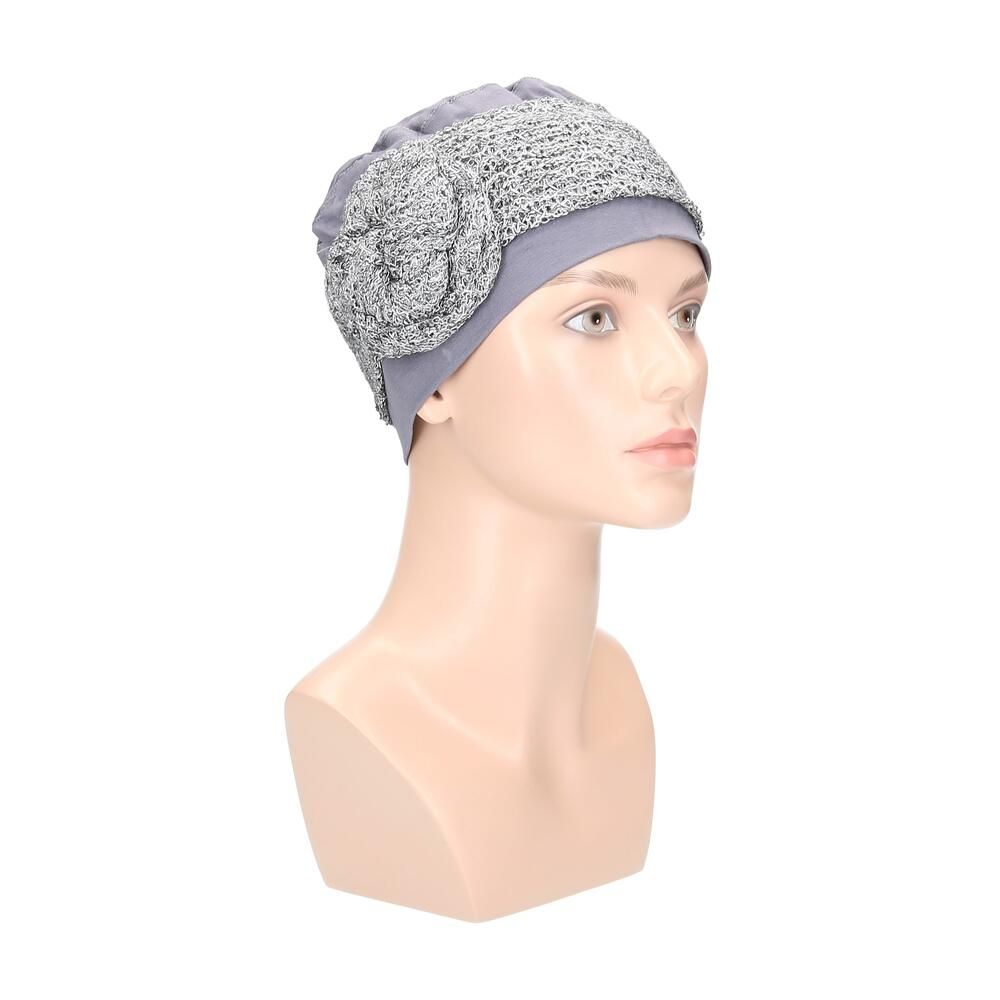 Grau/Silberfarbener Turban auf einer Büste. Der Turban hat eine verzierte Krempe und eine blütenförmige Applikation.