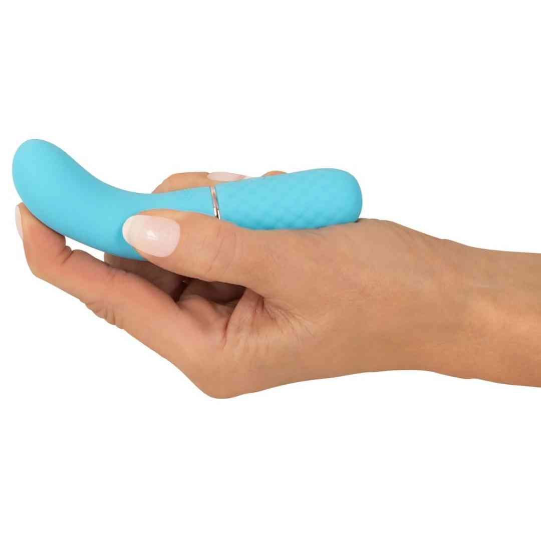 Türkisfarbener Vibrator in Hand gehalten. Gebogene Form, Rautenmuster, goldfarbener Ring.