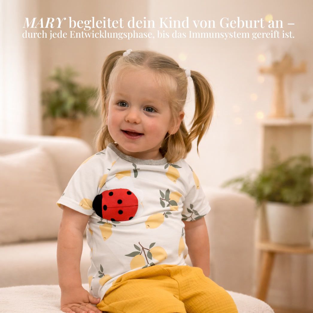 Kleinkind in Shirt mit Marienkäfer-Applikation. Text: MARY begleitet dein Kind von Geburt an.
