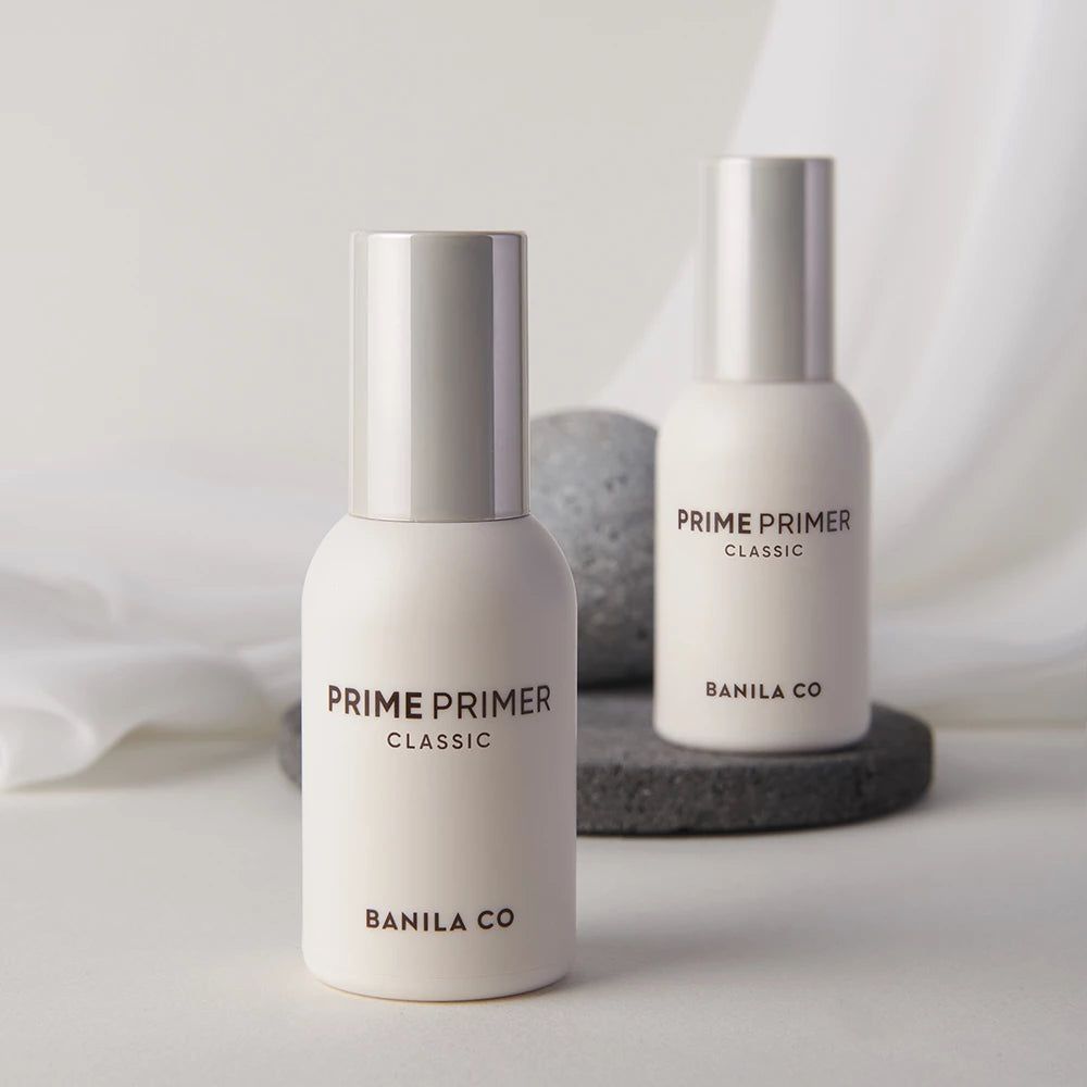 Zwei weiße Flaschen BANILA CO Prime Primer Classic auf einem Stein.