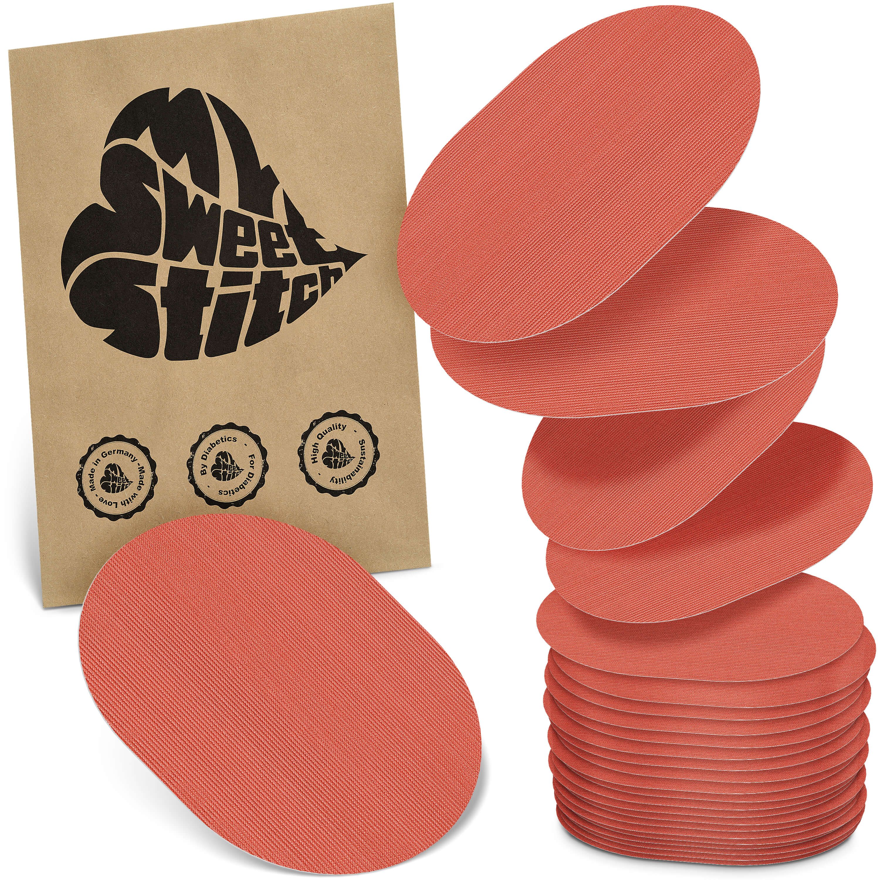 Korallenfarbene, ovale Pflaster. Eine Papiertüte mit Logo und Siegeln liegt daneben. Stapel von Pflastern.