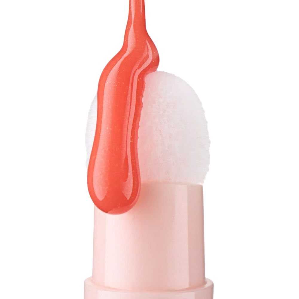 Ein korallenfarbener flüssiger Lippenstift mit Applikator auf weißem Hintergrund.