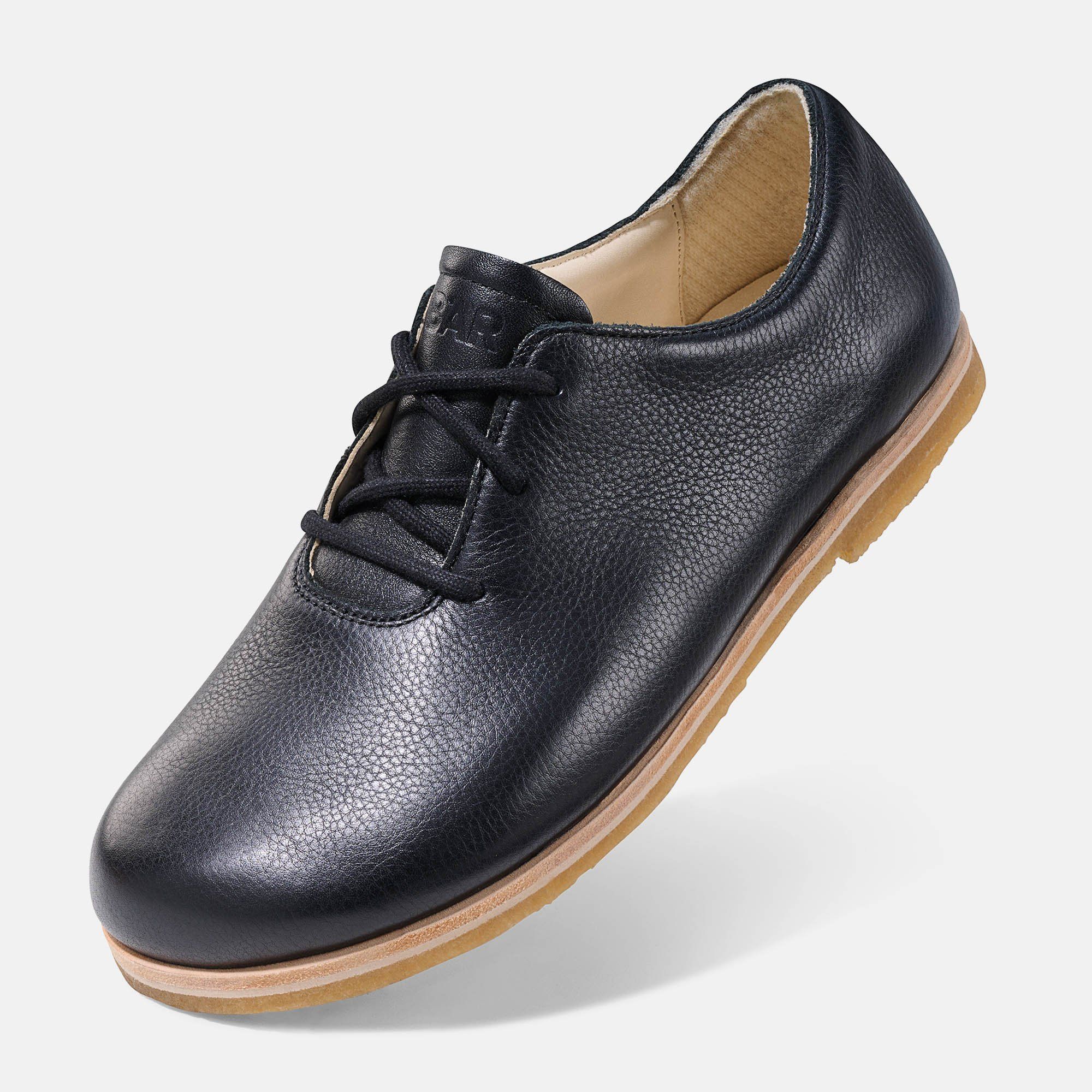 Schwarzer Lederschnürschuh. Helle Sohle. Schuh schräg gestellt.