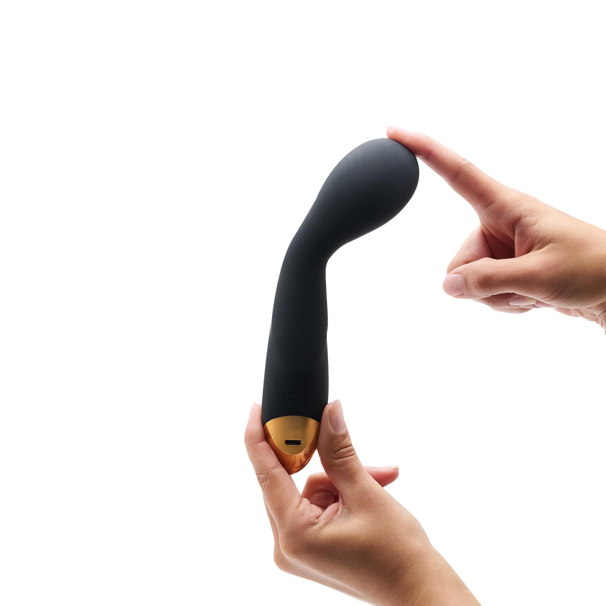 Schwarzer Massage-Wand, gehalten von zwei Händen. Der Kopf wird mit einem Finger berührt.