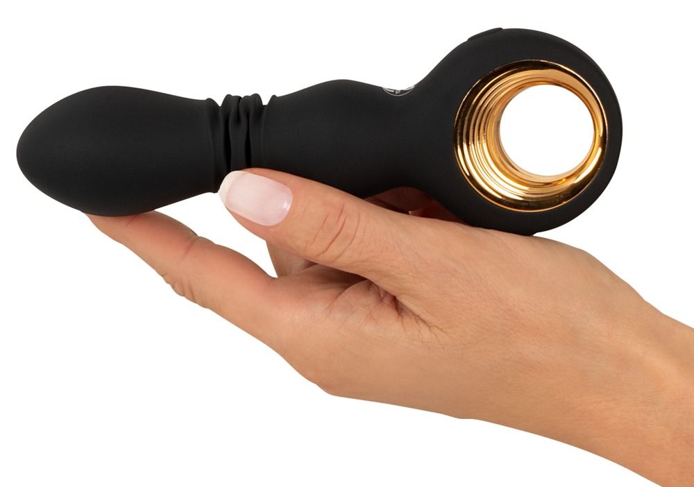 Schwarzer Vibrator in einer Hand gehalten. Goldfarbener Ring. Geriffelte Textur am Schaft. Weißer Nagellack.