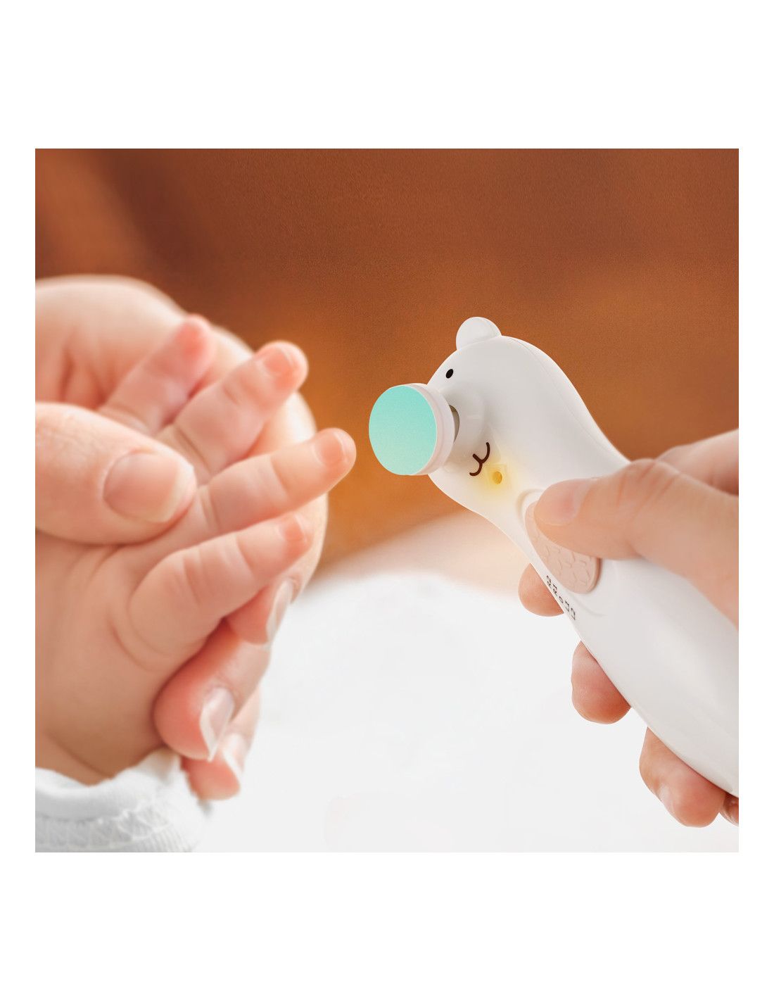 Weißes Nagelpflegegerät Happy Bear in Anwendung. Ein Finger eines Babys wird bearbeitet.