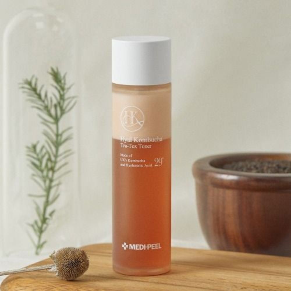 Flasche mit weißem Deckel. Aufschrift: Hyal Kombucha Tea Tox Toner. Marke: MEDI-PEEL. Auf Holzbrett.