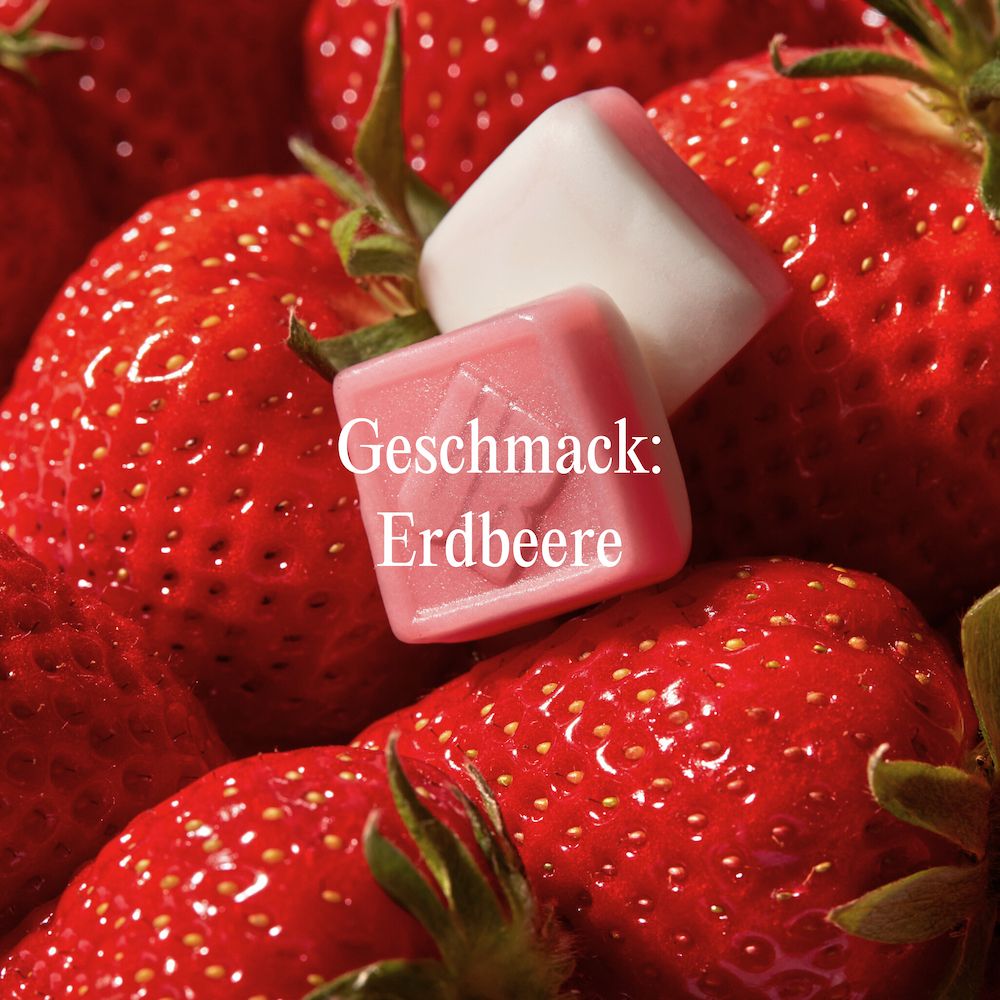 Gummies auf Erdbeeren. Text: Geschmack: Erdbeere. Rosa-weiße Gummies mit geprägtem Buchstaben "U".