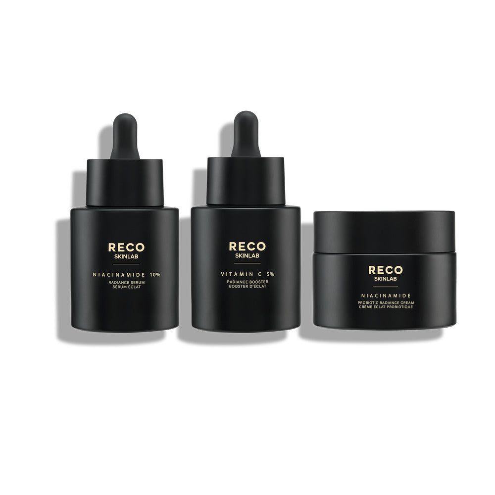 Drei schwarze Flakons und ein Tiegel. Auf den Flakons steht "RECO SKINLAB". Beschriftung: Niacinamide 10%, Vitamin C 3%.