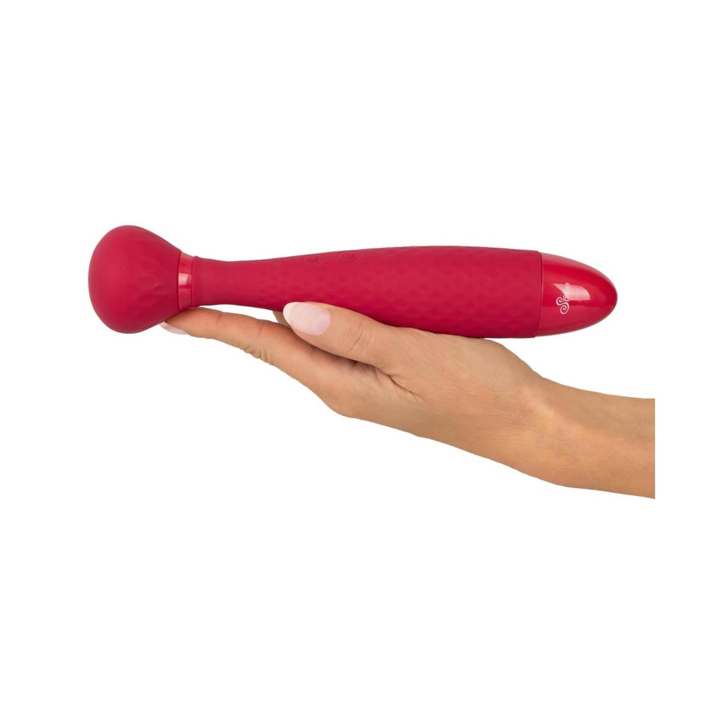 Roter Vibrator in einer Hand gehalten. Abgerundeter Kopf, strukturiertes Design. Auf weißem Hintergrund.