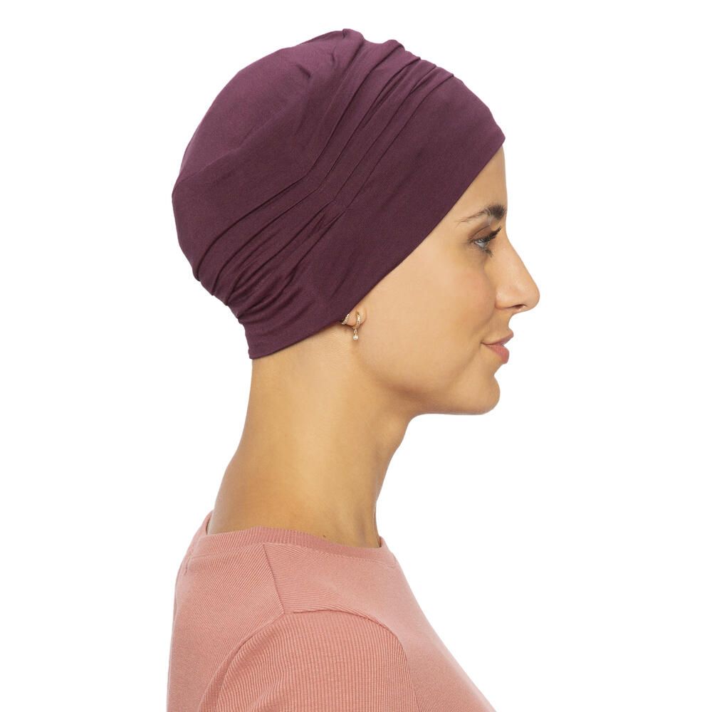 Burgunderfarbener Turban. Seitenansicht. Gerüschte Textur. Angenehmes Material. Auf hellem Hintergrund. Frau mit Ohrringen.