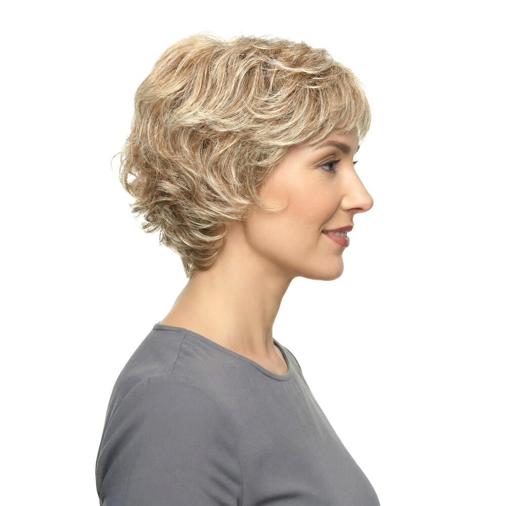 Perücke Iris von Lofty. Kurze, blonde Kunsthaarperücke mit gewellter Struktur. Frau trägt graues Oberteil. Seitenansicht.