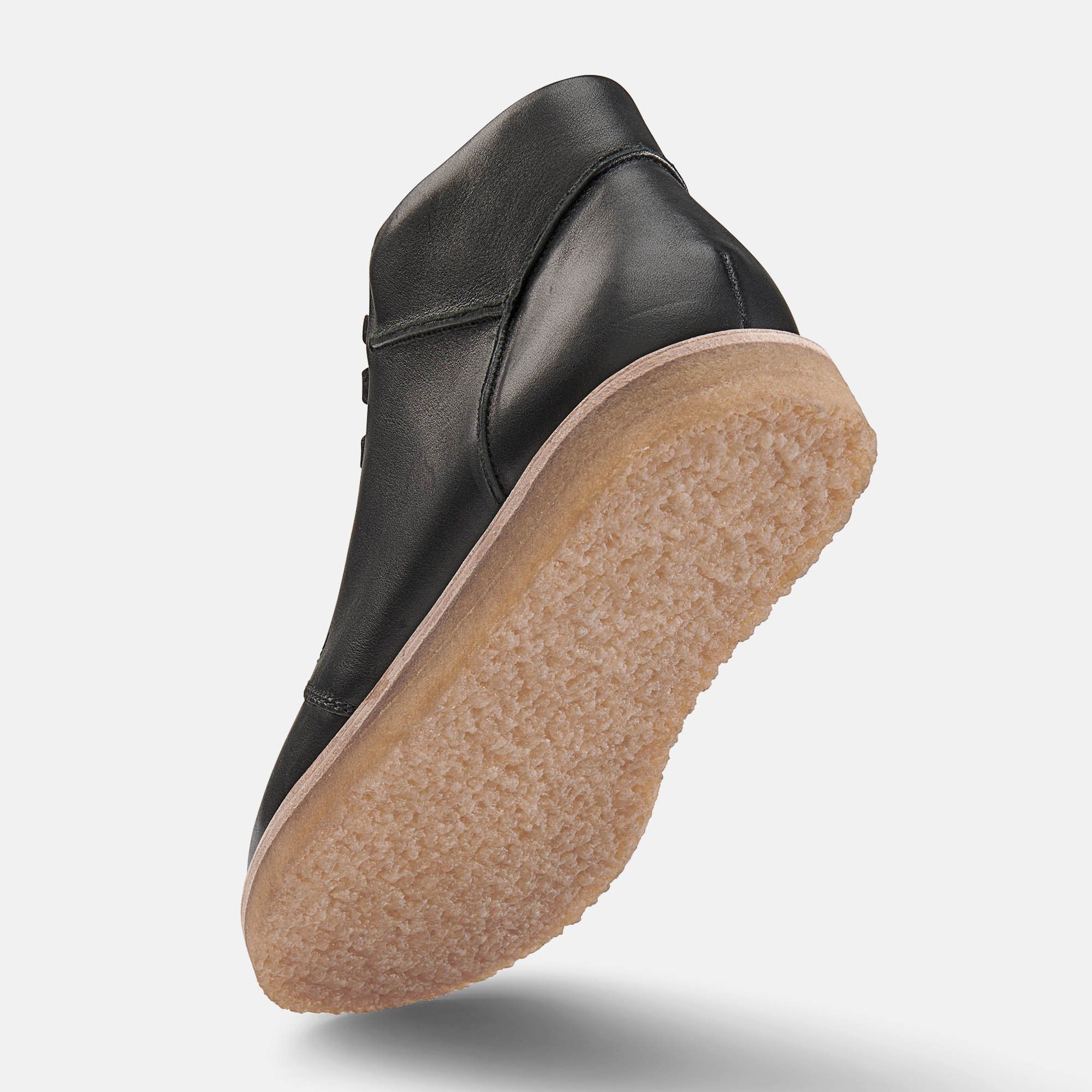 Schwarze Herren-Stiefelette mit hellbrauner Sohle, von unten gesehen. Detailansicht der Sohle und des Schuhs.