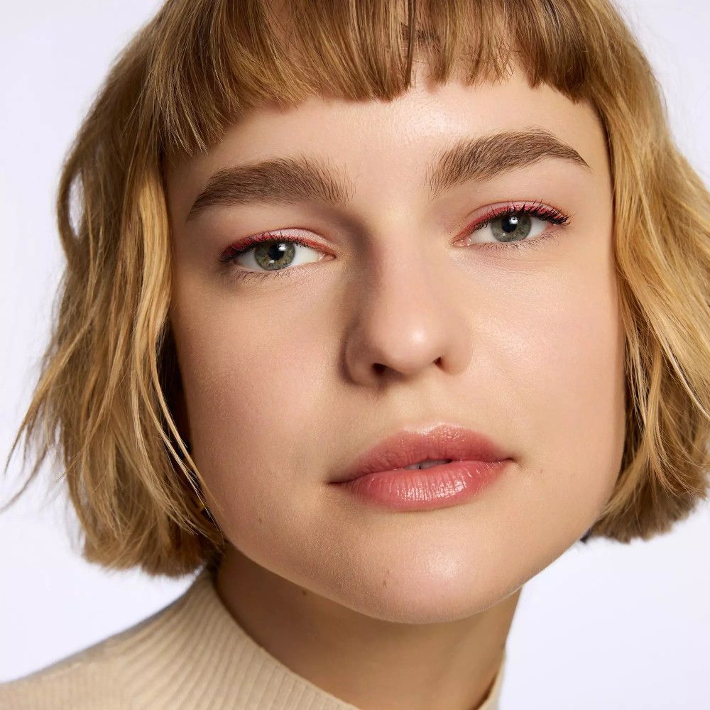 Porträt einer Frau mit rotem Eyeliner. Kurze blonde Haare.