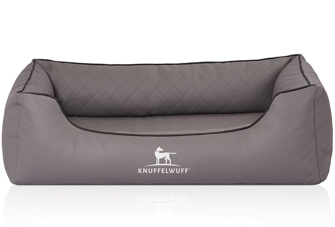 Graues Hundebett mit gesteppter Liegefläche und erhöhtem Rand. Schwarze Paspelierung. Logo: Knuffelwuff.