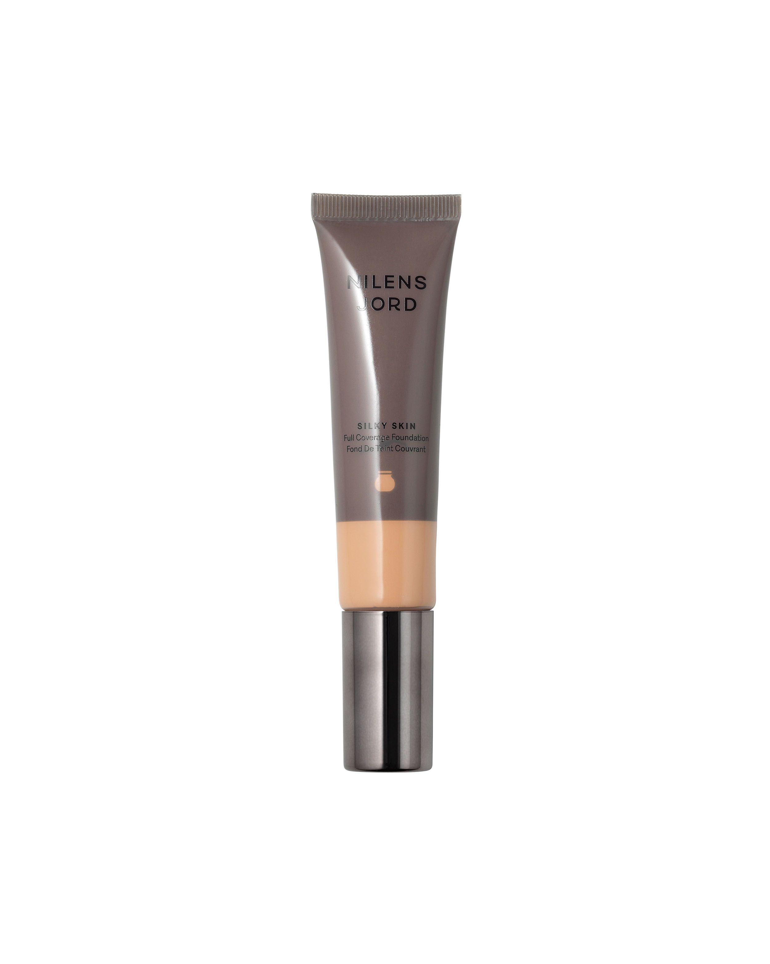 Nilens Jord Silky Skin Foundation in einem schmalen Schlauch mit silbernem Verschluss. Die Foundation ist in einem hellen Hautton gehalten.