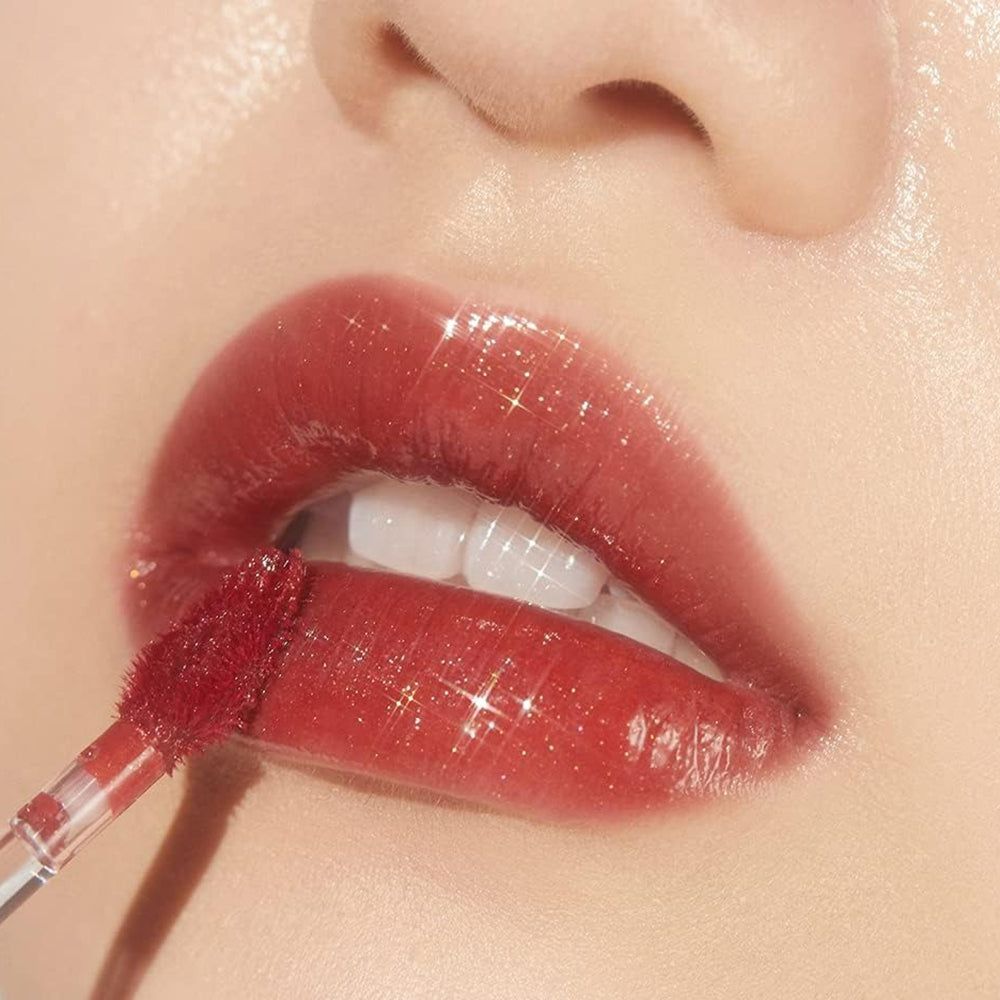 Nahaufnahme von Lippen mit rotem Glanz-Lipgloss. Ein Applikator wird verwendet.