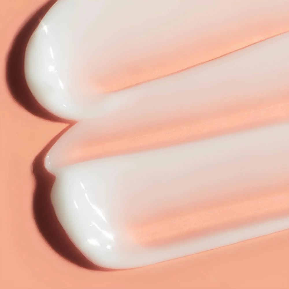 Nahaufnahme von zwei cremigen Streifen. Cremefarbene Textur auf rosa Hintergrund.