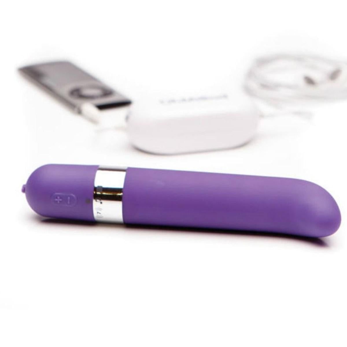 Lila Vibrator mit Zubehör. Neben dem Vibrator liegen ein MP3-Player, ein Ladekabel und eine Ladestation.