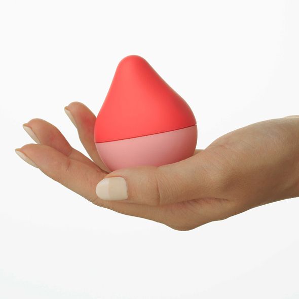 Zweifarbiges, tropfenförmiges Objekt in einer Handfläche. Oberteil rot, Unterteil rosa. Glatte Oberfläche.