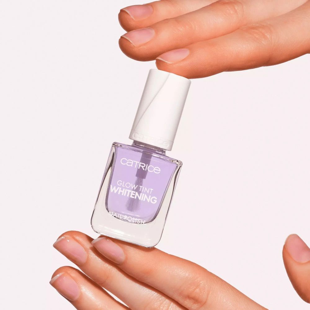 Nagellackflasche in Händen gehalten. Lila Farbton, Aufschrift 'Glow Tint Whitening'.