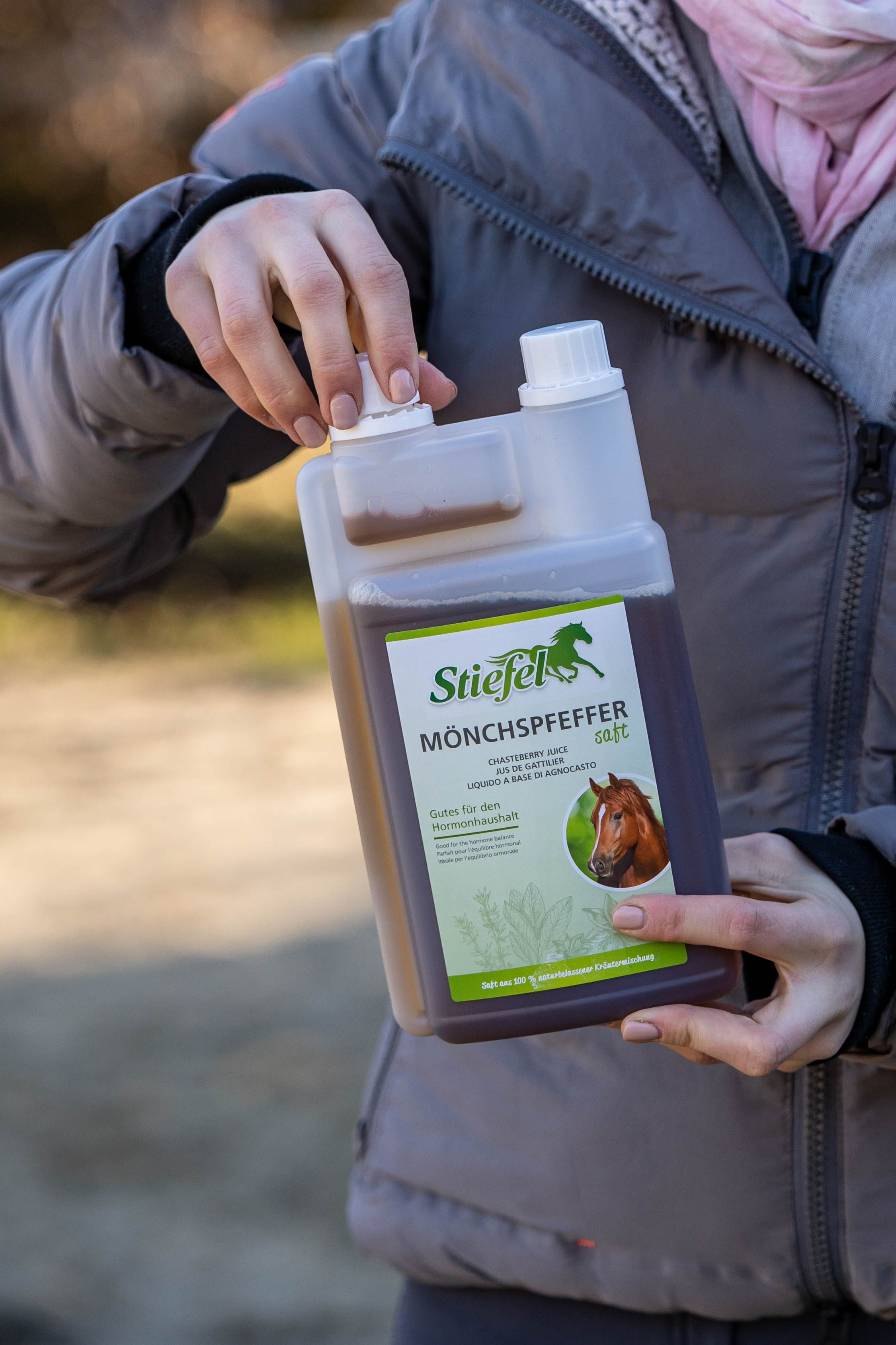 Person hält eine Flasche Stiefel Mönchspfeffersaft. Die Flasche ist durchsichtig mit brauner Flüssigkeit und weißem Deckel.