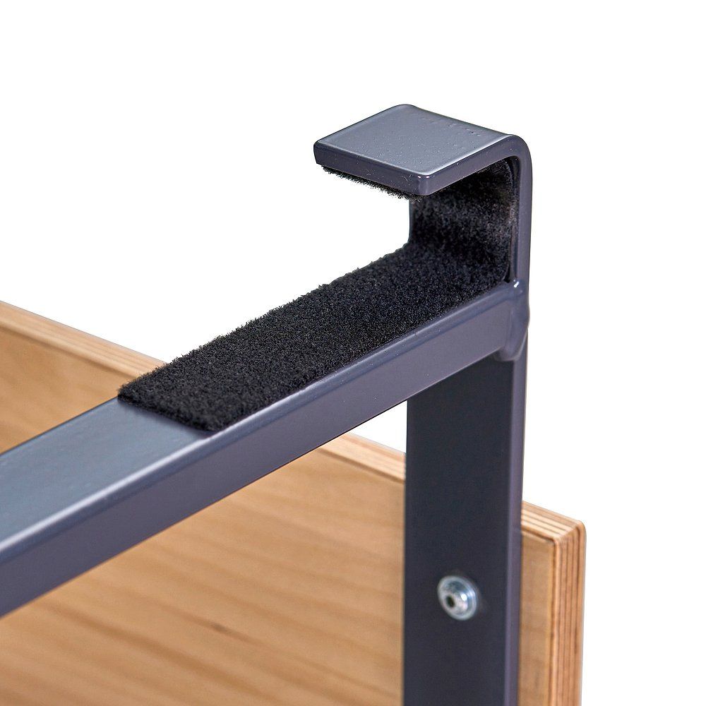 Nahaufnahme des Sprossenwandsitzes. Holzplatte, Metallrahmen mit schwarzer Polsterung. Haken zum Einhängen.