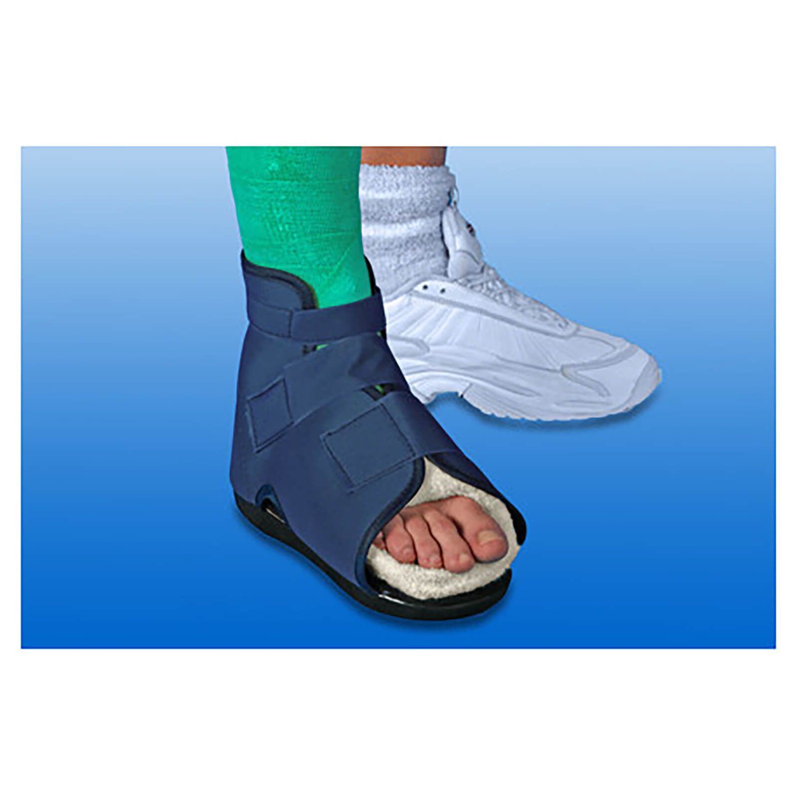 Blauer Gehschuh mit Klettverschlüssen, offene Zehenpartie, innen weißes Fell. Fuß mit grünem Verband. Zweiter Schuh im Hintergrund.