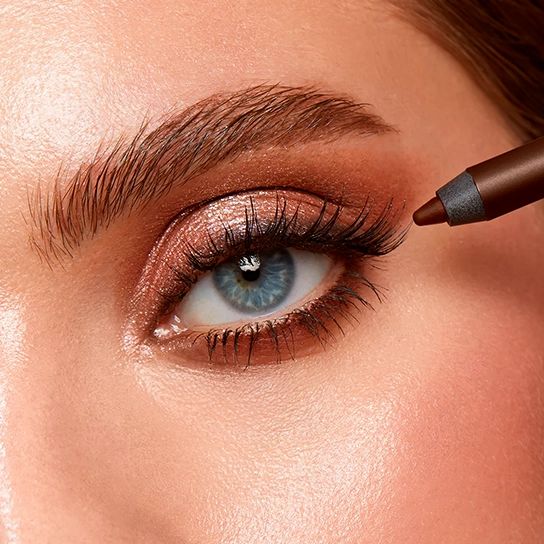 Nahaufnahme eines Auges mit braunem Lidschatten und Eyeliner. Ein brauner Stift wird verwendet.