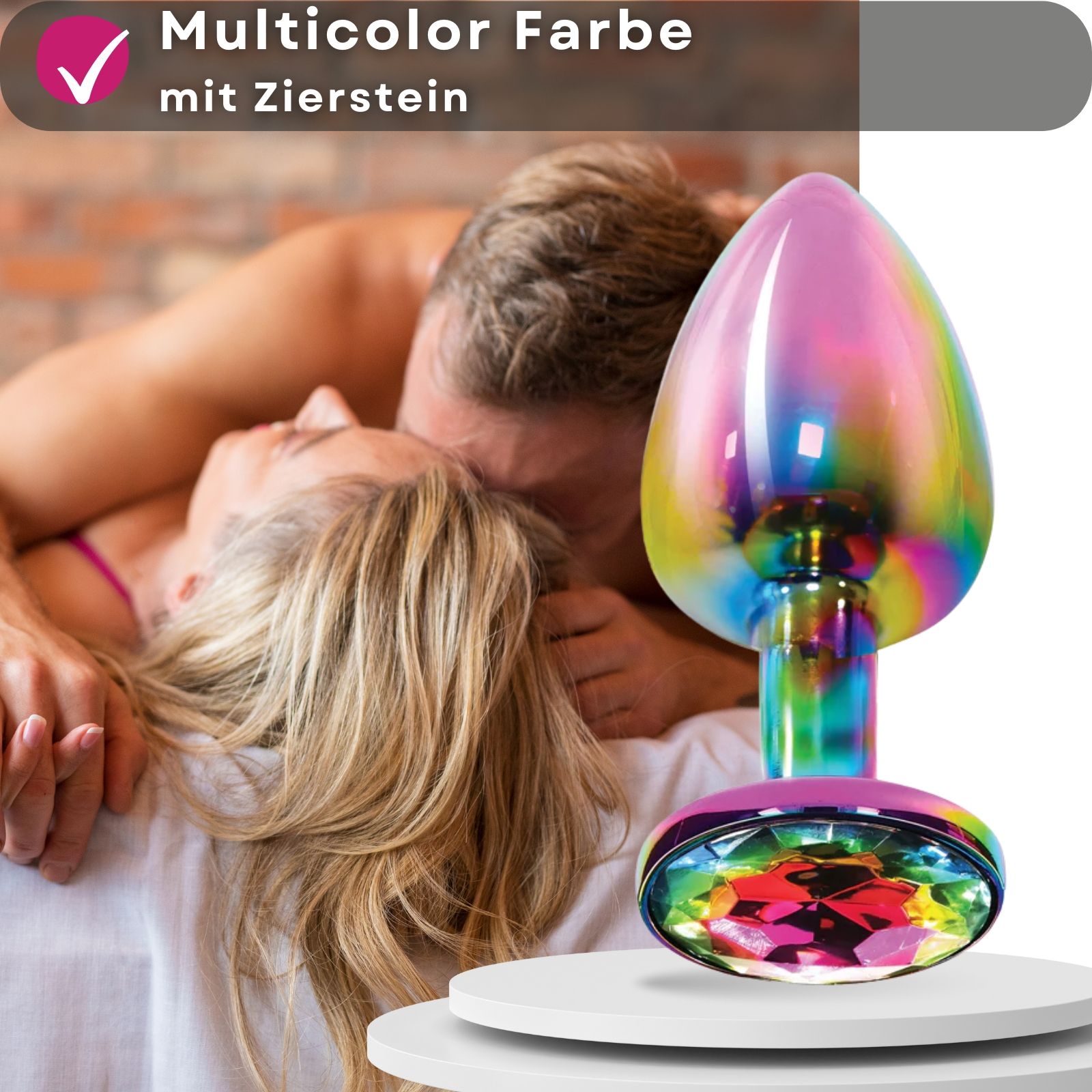 Multicolor Analplug mit Zierstein. Produktabbildung vor Paar. Auf Podest platziert.