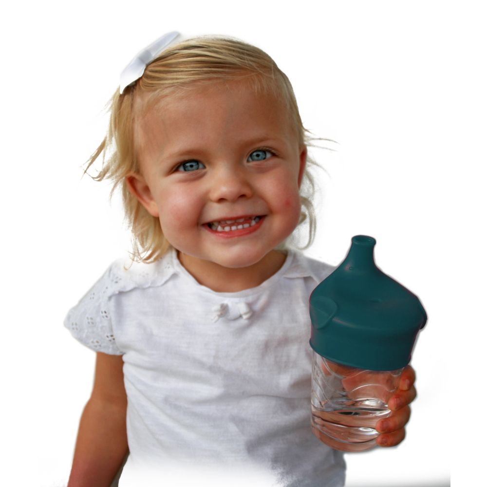 Kleines Mädchen hält ein Glas Wasser, das mit einem blaugrünen Silikon-Deckel mit Schnabelaufsatz verschlossen ist.