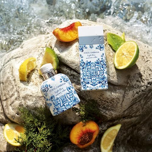Zwei Parfümflakons auf einem Felsen, umgeben von Früchten. Aufschrift: Dolce & Gabbana Light Blue Summer Vibes.