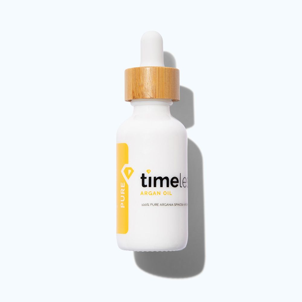 Weiße Flasche mit Holzdeckel und Pipette. Gelbes Etikett mit "timeless" und "Argan Oil".