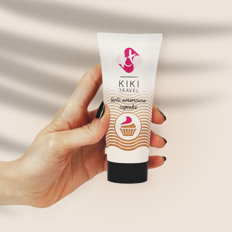 Hand hält Tube Gleitgel "KIKI TRAVEL" mit Aufdruck "tarta americana cupcake".