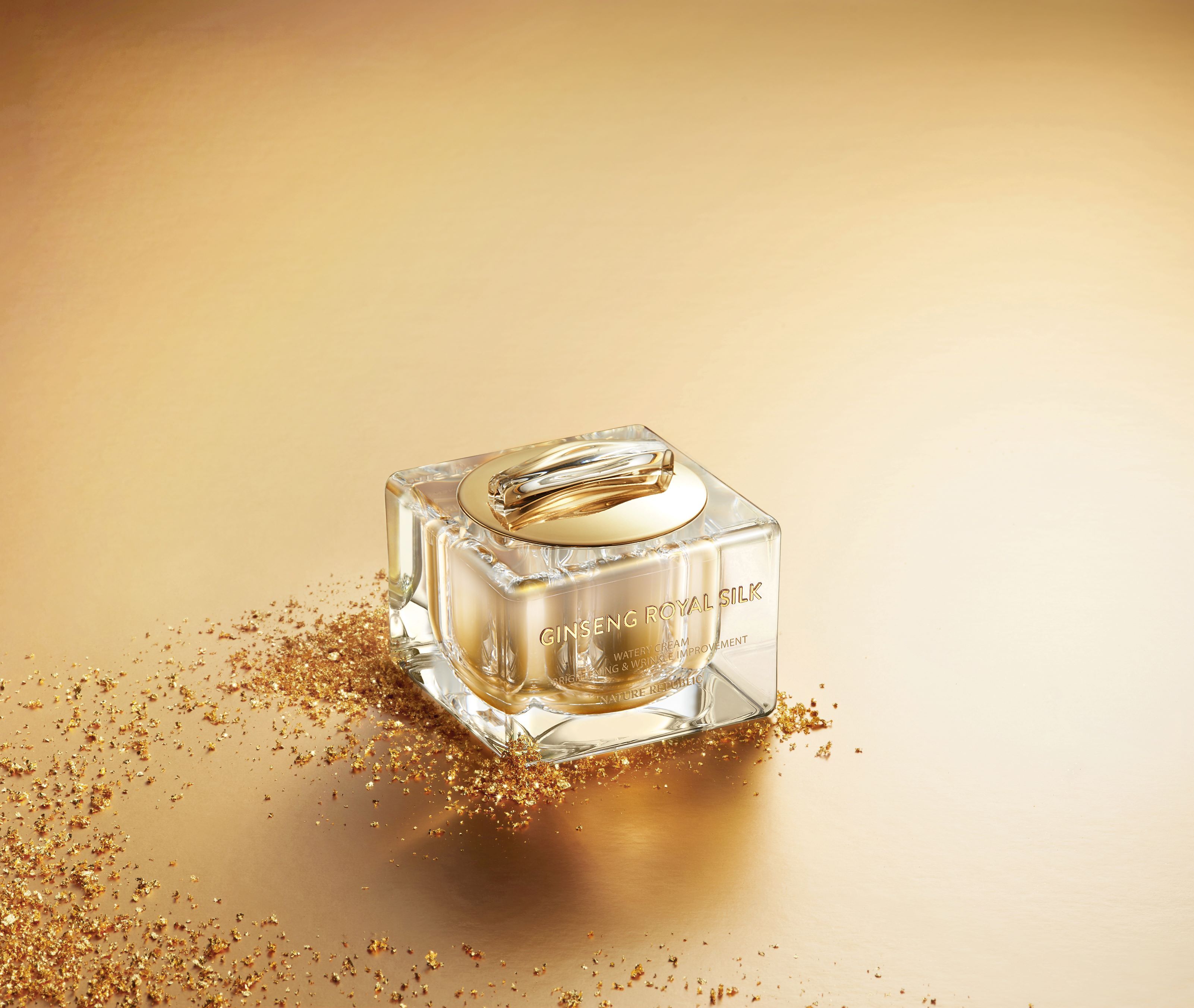 Creme-Glasbehälter auf goldenem Untergrund mit Goldflocken. Aufschrift: GINSENG ROYAL SILK.