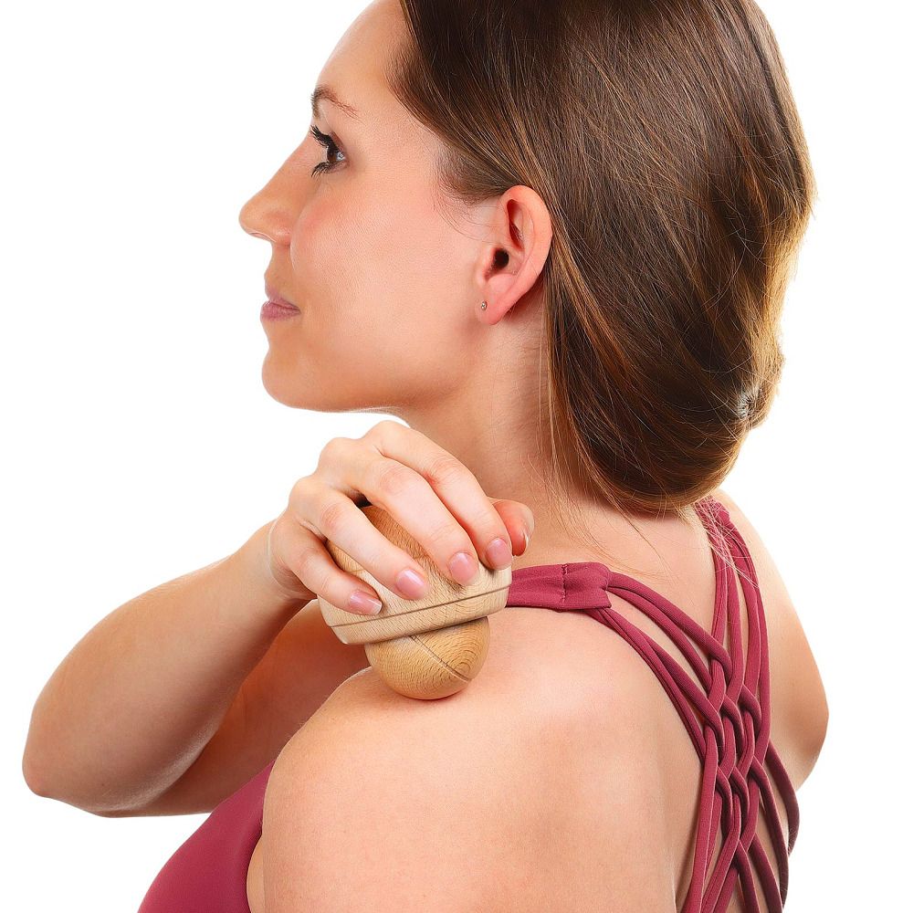 Person verwendet Holz-Massageroller an der Schulter. Besteht aus einer Kugel und einer Halterung. Natürliches Holz.