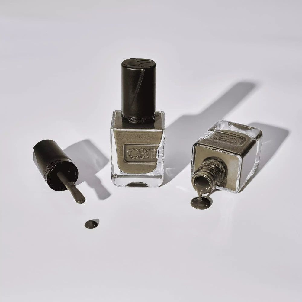 Zwei Nagellackflaschen liegen auf einer weißen Oberfläche. Eine Flasche ist umgekippt und der Lack ist ausgelaufen.