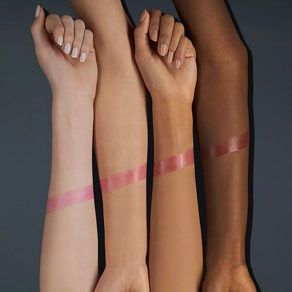 Vier Arme mit unterschiedlichen Hauttönen zeigen Lippenbalsam-Swatches. Der Balsam ist rosa und glänzend.