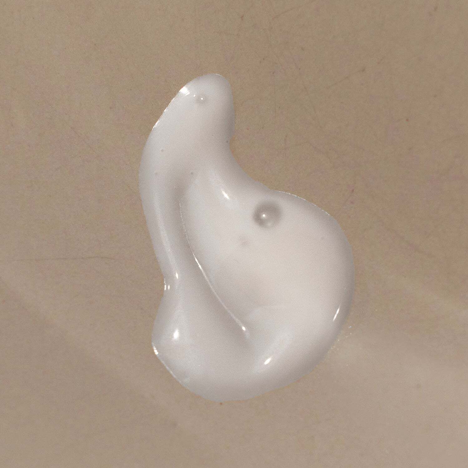 Nahaufnahme einer weißen, cremigen Substanz. Tropfenförmig, mit einer kleinen Erhebung. Glatte Oberfläche.