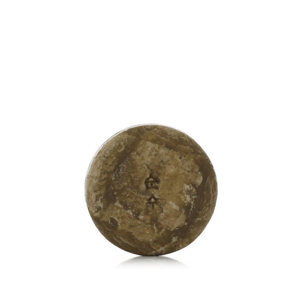 Runder, brauner Gegenstand mit eingeprägten Schriftzeichen. Oberfläche strukturiert. Auf weißem Hintergrund.