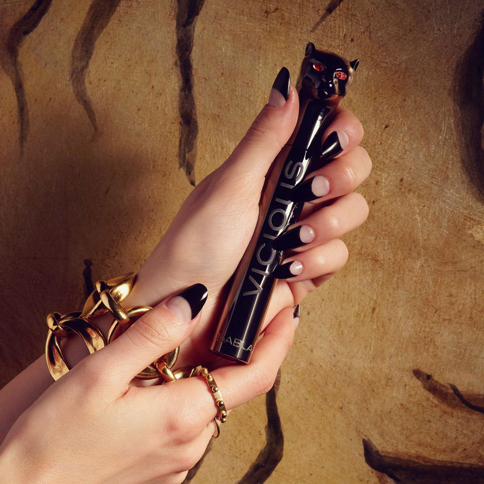 Hände halten eine schwarze Mascarahülse mit dem Schriftzug 'VICIOUS'.