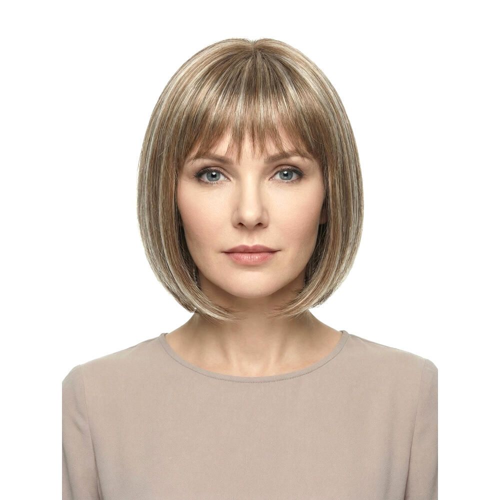 Perücke mit kurzem, blondem Haar und Pony. Die Frau trägt ein beiges Oberteil. Frontansicht.