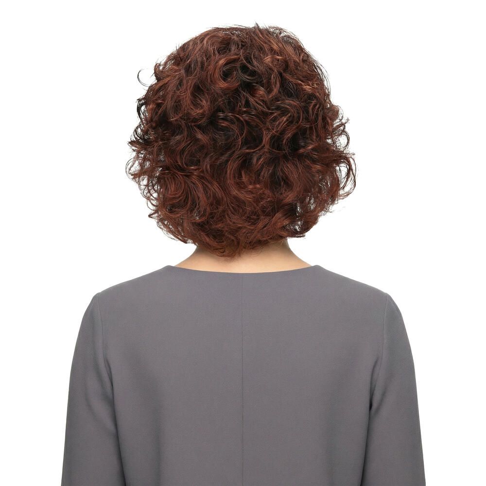 Rückansicht einer Frau mit brauner, lockiger Perücke. Graues Oberteil. Weißer Hintergrund.