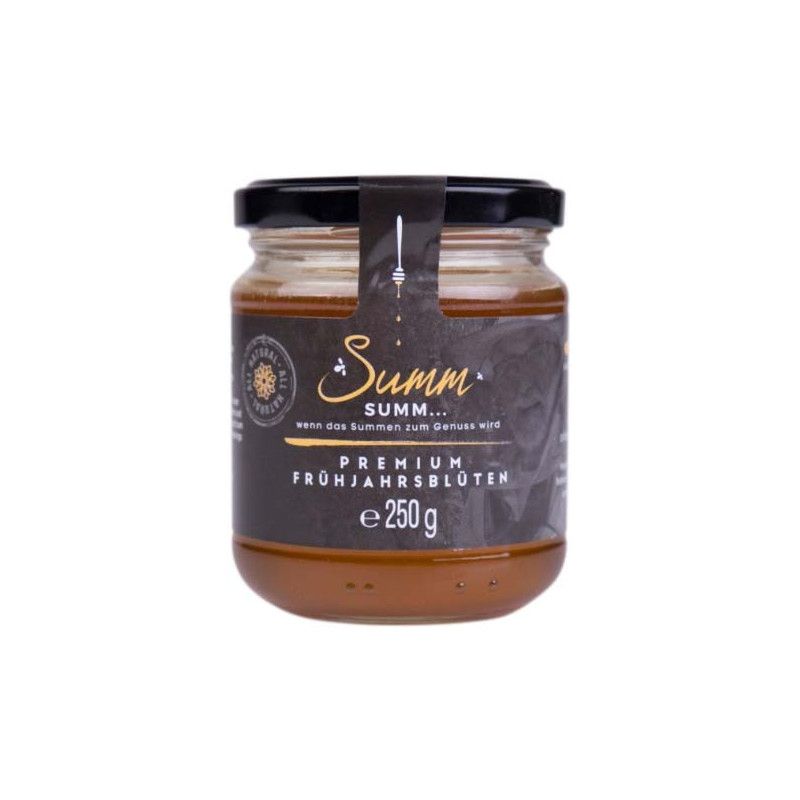 Glas Honig mit schwarzem Deckel und Etikett. Aufschrift: Summ... Premium Frühjahrsblüten, 250g.