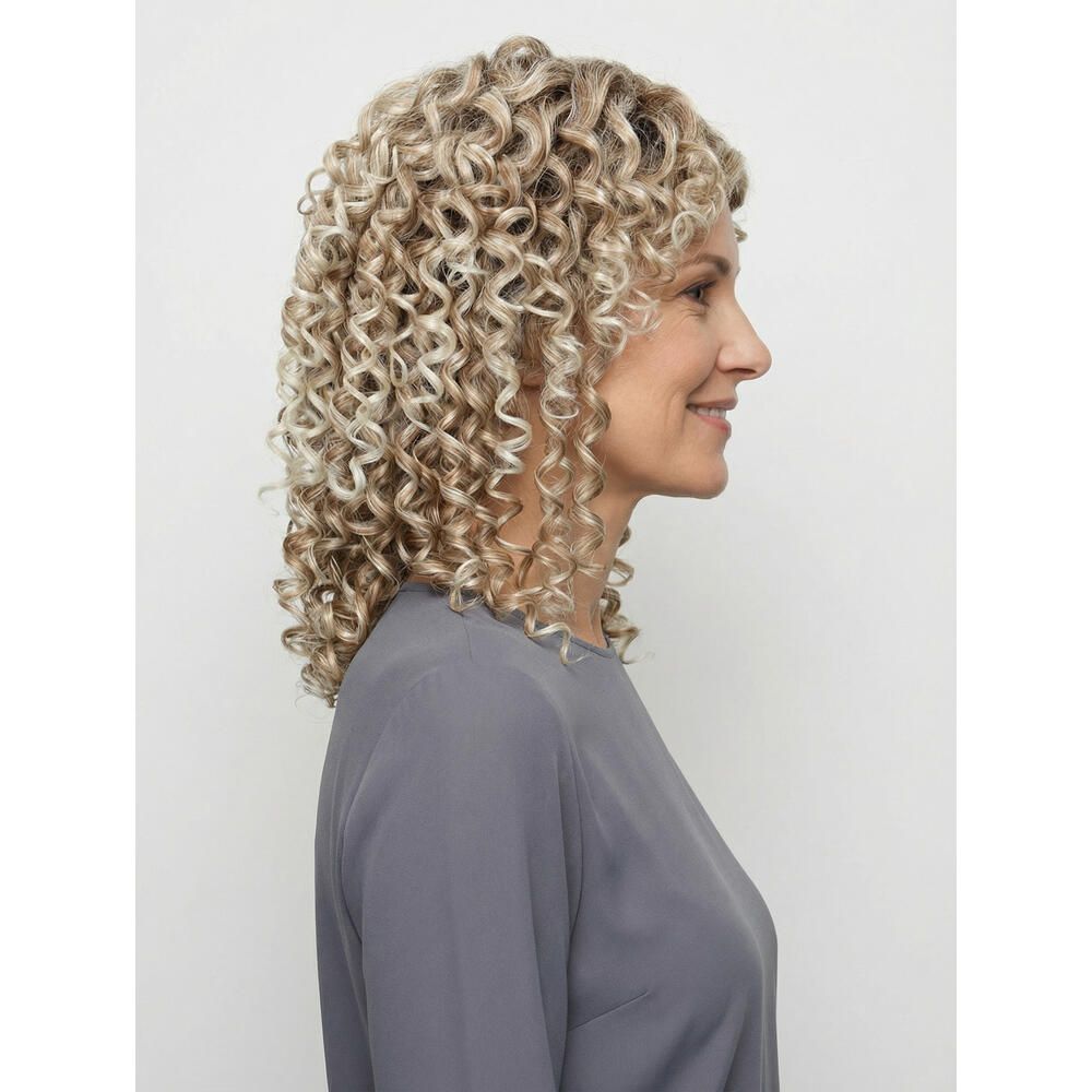 Frau mit lockiger, blond gefärbter Perücke. Seitenansicht, lächelnd, graue Bluse.