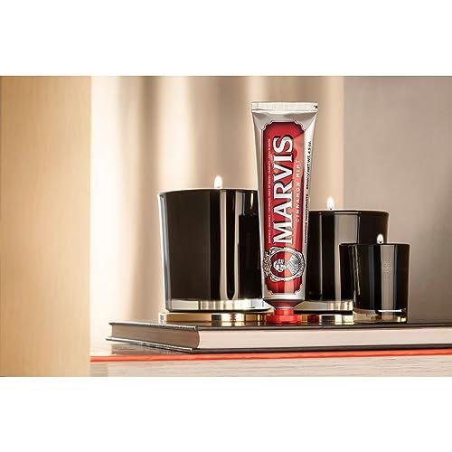 Zahnpasta-Tube MARVIS CINNAMON MINT neben Kerzen. Tube mit rotem Schriftfeld und rotem Deckel.