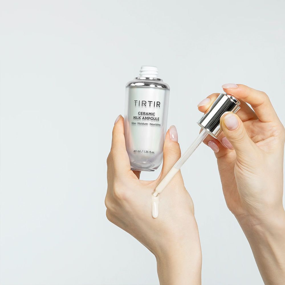 Hände tragen TIRTIR Ceramic Milk Ampoule auf, mit Tropfen auf der Haut.