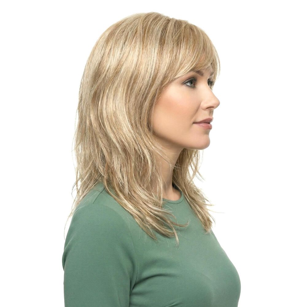Blond gewellte Perücke mit Pony, Seitenansicht einer Frau in grünem Oberteil. Haare fallen bis zu den Schultern.